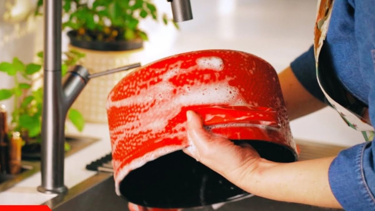 Pessoa lavando facilmente uma panela de cerâmica Ceraflame na pia, demonstrando como limpar o utensílio corretamente.